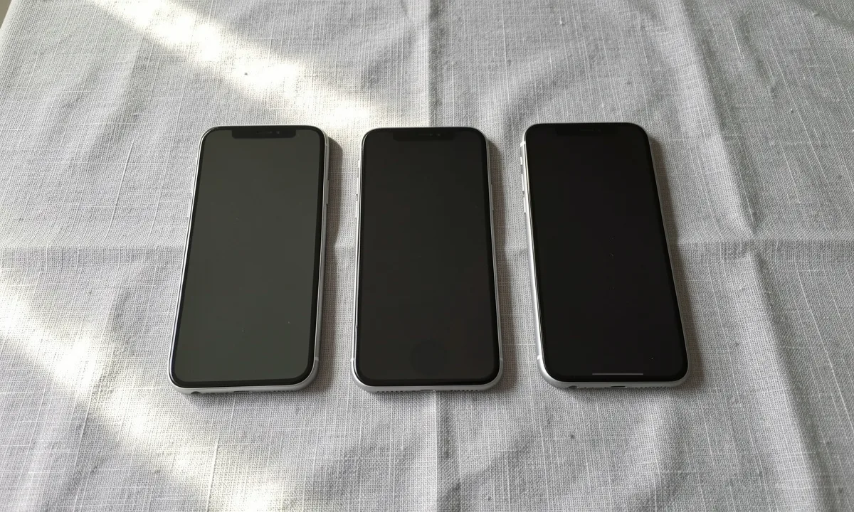 Three phones with dark screens side by side on a linen tablecloth